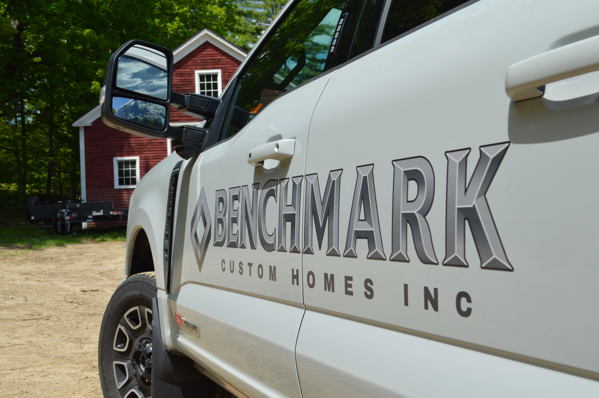 Benchmark Custom Homes Inc branded truck parked at a New England property
